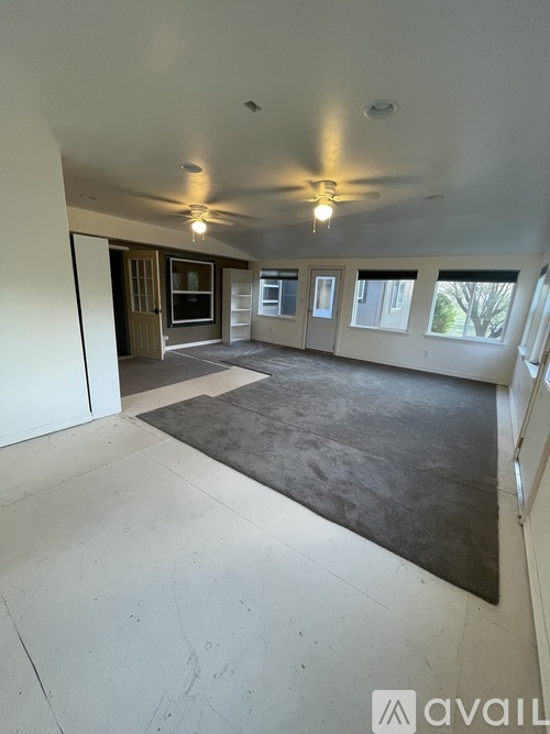 A spacious room with a ceiling fan and a rug on the floor.