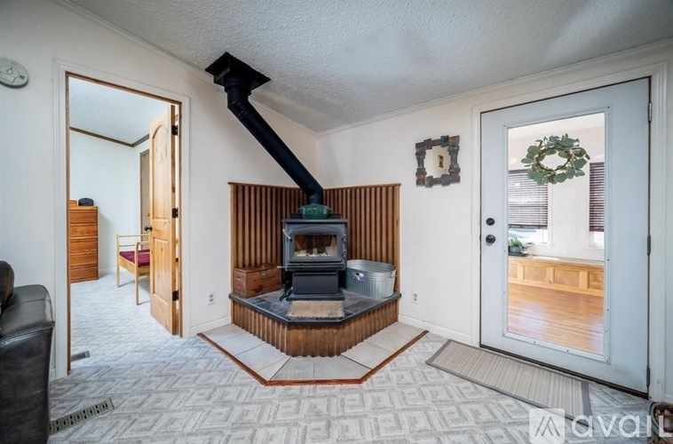 A wood stove is in a living room with a wreath on the door.