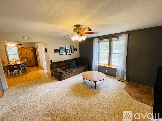 A living room with a brown couch and a ceiling fan.