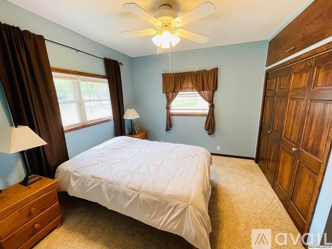 A bedroom with a bed, dresser, and window.