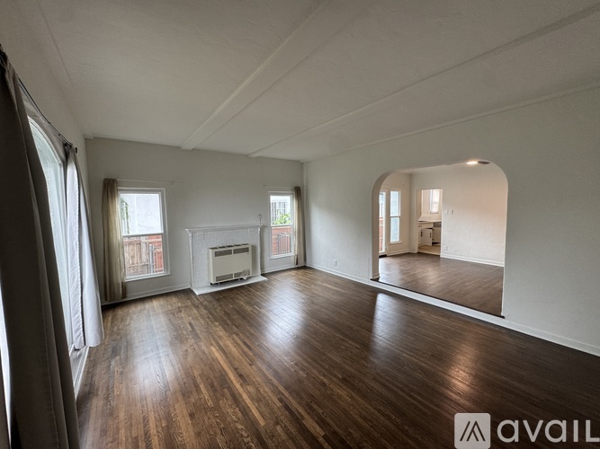 A spacious room with wooden floors and a large mirror on the wall.