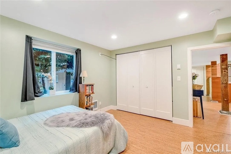 A bedroom with a large bed and a window with curtains.