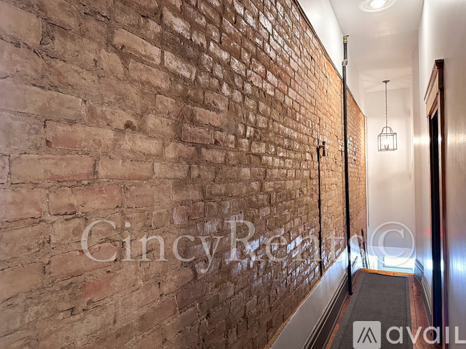 A hallway with a brick wall and a metal railing.