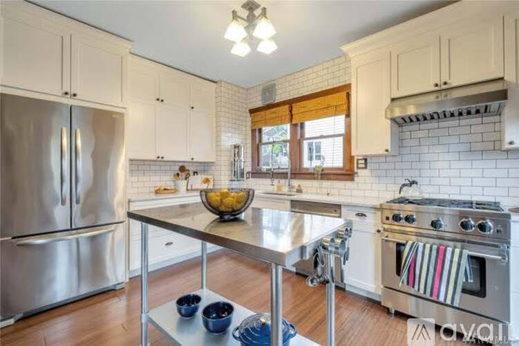 A modern kitchen with a stainless steel refrigerator, a stainless steel island, and a stainless steel stove.