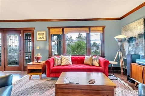 A living room with a red couch and a wooden coffee table.