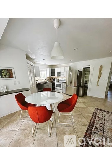 A modern kitchen with red chairs and a glass table.