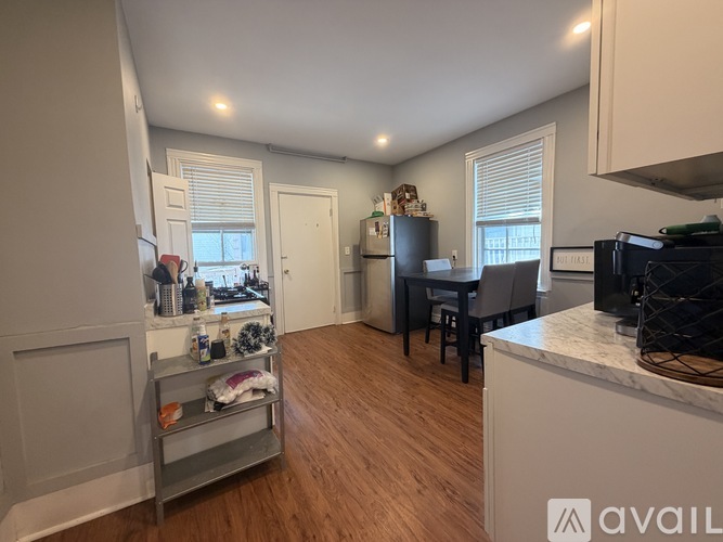 A kitchen with a refrigerator, a dining table with chairs, and a counter with a microwave.