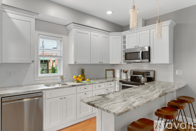 A kitchen with white cabinets and a marble countertop.