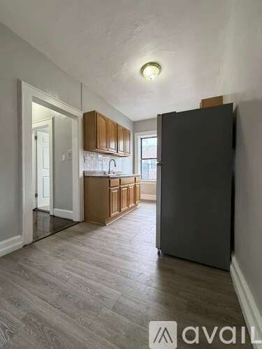 A kitchen with a black refrigerator and wooden cabinets.