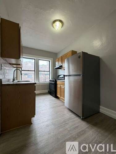 A kitchen with a refrigerator, sink, and cabinets.