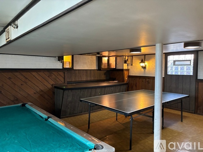 A room with a pool table and a bar area.