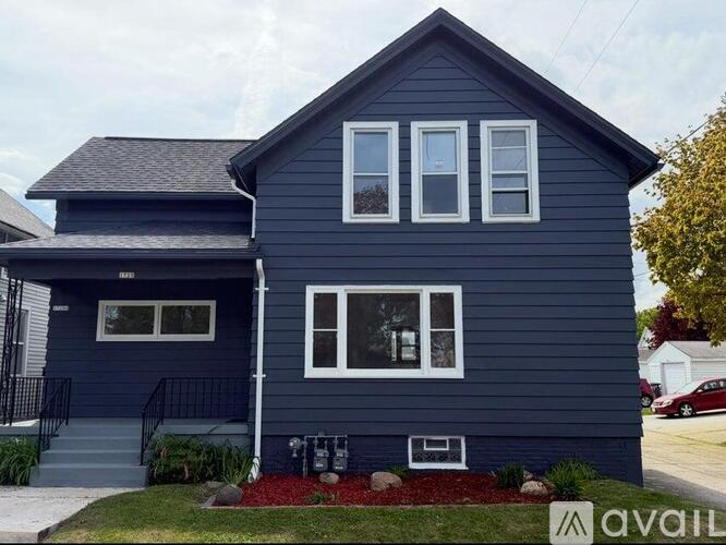 A blue house with a white window and a black fence.