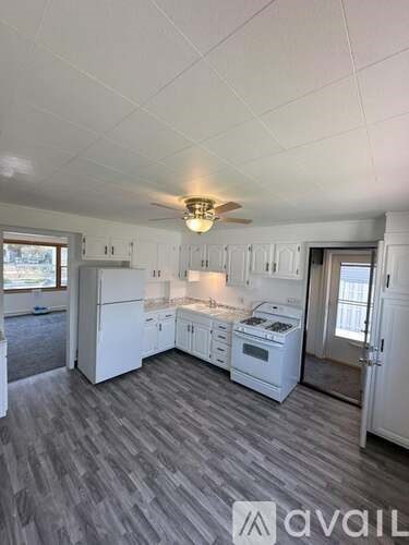 A kitchen with white appliances and a ceiling fan.