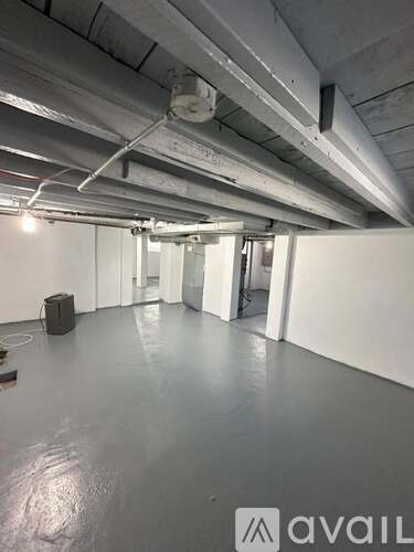 A spacious room with a concrete floor and exposed ceiling beams.