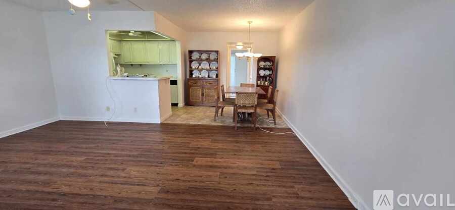 A room with wooden floors and a kitchenette in the corner.