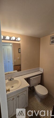 A bathroom with a toilet, sink, and mirror.