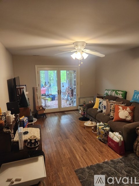A living room with a brown couch and a ceiling fan.