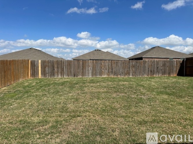 A backyard with a wooden fence and a grassy field.