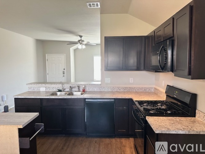 A kitchen with black cabinets and a granite countertop.