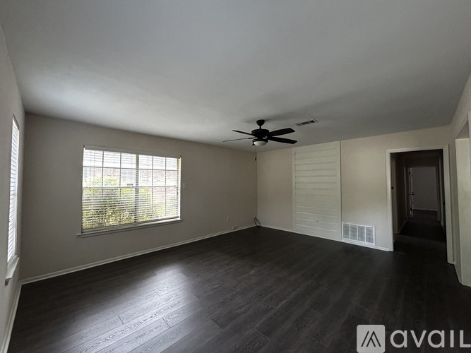 A spacious room with a ceiling fan and a window with blinds.