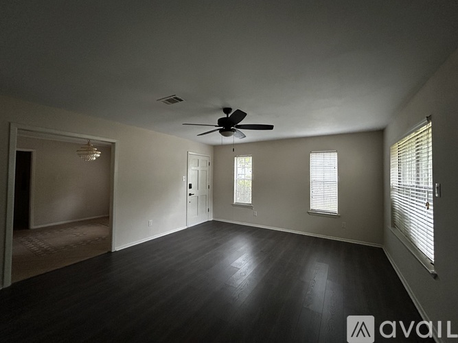 A spacious room with a ceiling fan and hardwood flooring.