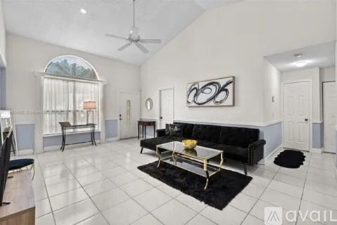A living room with a black couch and a painting on the wall.
