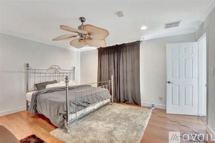 A bedroom with a bed, a ceiling fan, and a rug.