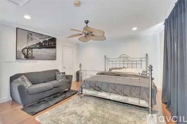 A bedroom with a bed, couch, and a ceiling fan.