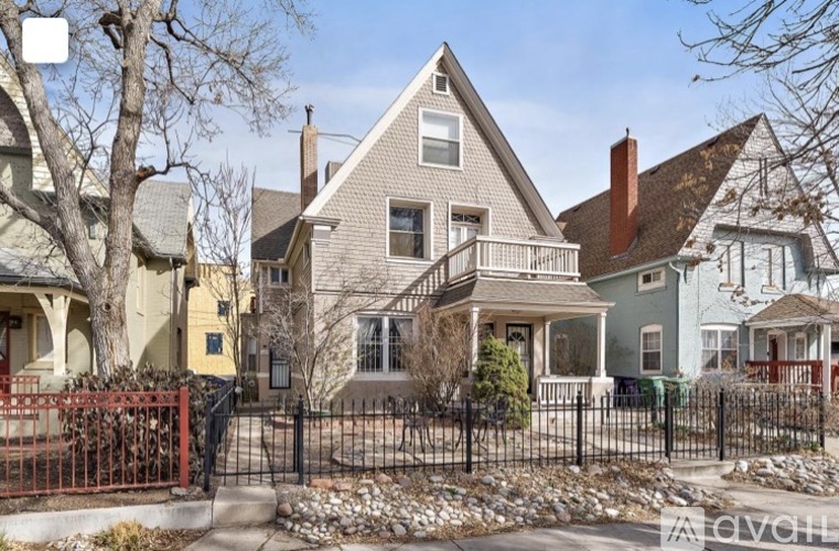 A house with a grey roof and a red fence in front.