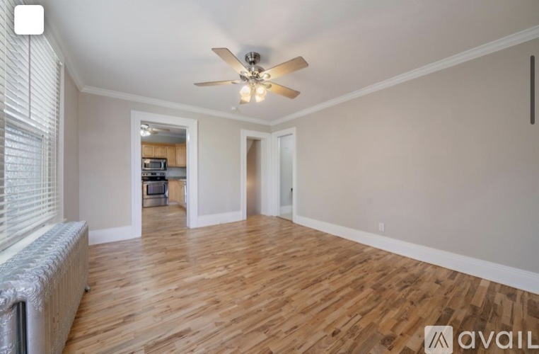 A spacious room with wooden flooring and a ceiling fan.