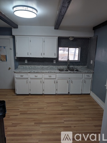 A kitchen with wooden floors and white cabinets is available for rent.