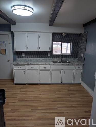 A kitchen with wooden floors and white cabinets is available for rent.