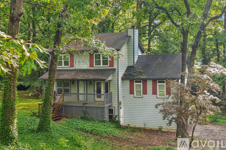 A house with a red and white striped window is surrounded by trees.