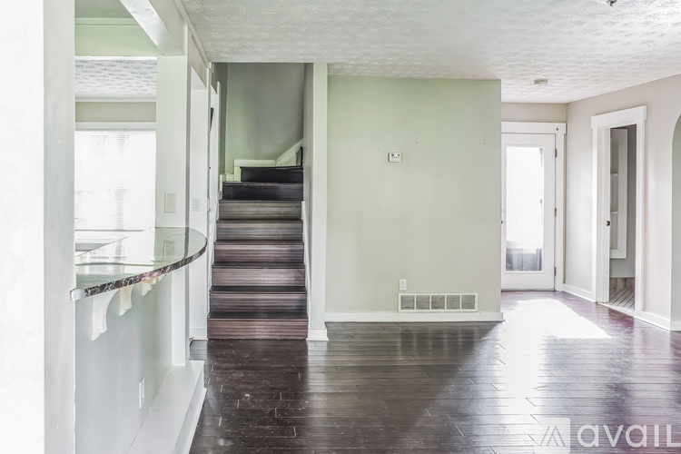 A staircase with a glass railing leads to a bedroom.