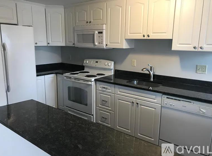 A kitchen with white cabinets and black countertops.