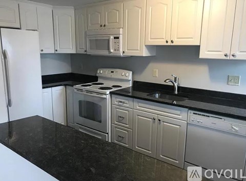 A kitchen with white cabinets and black countertops.