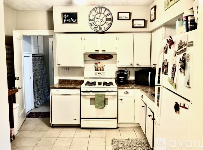 A white kitchen with a stove top oven and a refrigerator.