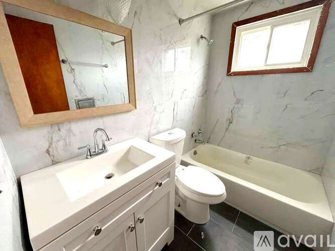 A bathroom with a marble wall and a white bathtub.