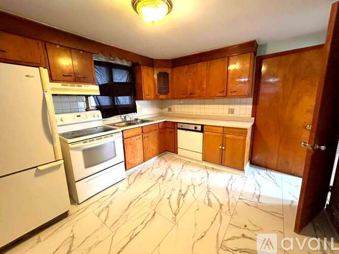 A kitchen with wooden cabinets and marble flooring.