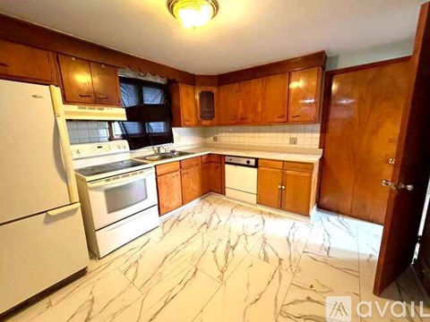 A kitchen with wooden cabinets and marble flooring.