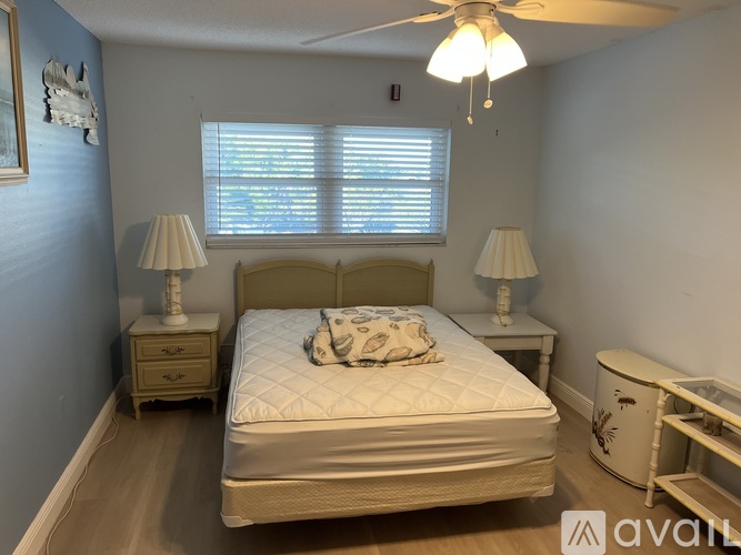A bedroom with a bed, two lamps, and a ceiling fan.