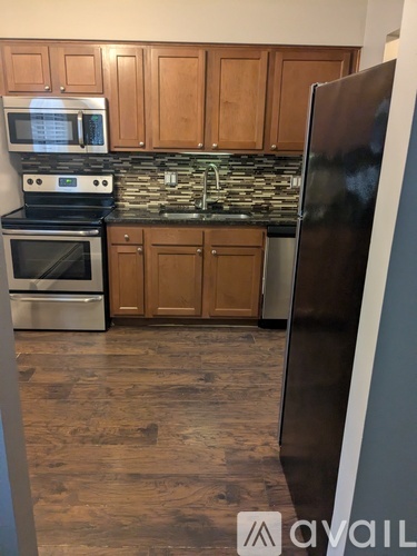 A kitchen with wooden cabinets and a black refrigerator.