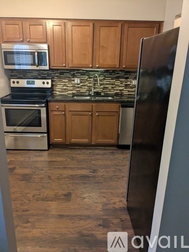 A kitchen with wooden cabinets and a black refrigerator.