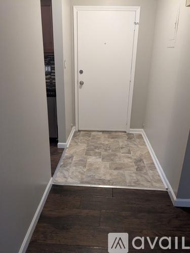 A hallway with a tiled floor and a white door.