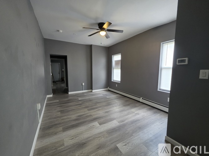 A spacious room with a ceiling fan and wooden flooring.
