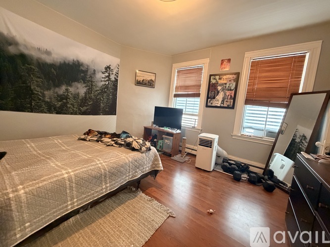 A bedroom with a large bed and a wall mural of a forest scene.