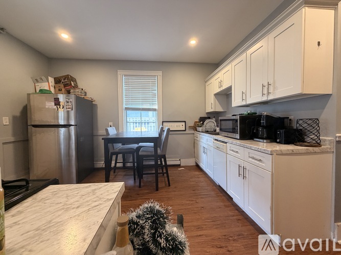 A kitchen with white cabinets and a dining table with chairs.