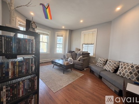A living room with a bookshelf filled with books on the left side and a grey sofa in the center.
