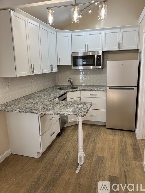 A kitchen with white cabinets and a granite countertop.