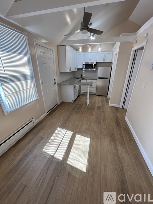 A spacious kitchen and living room with wood flooring and white walls.